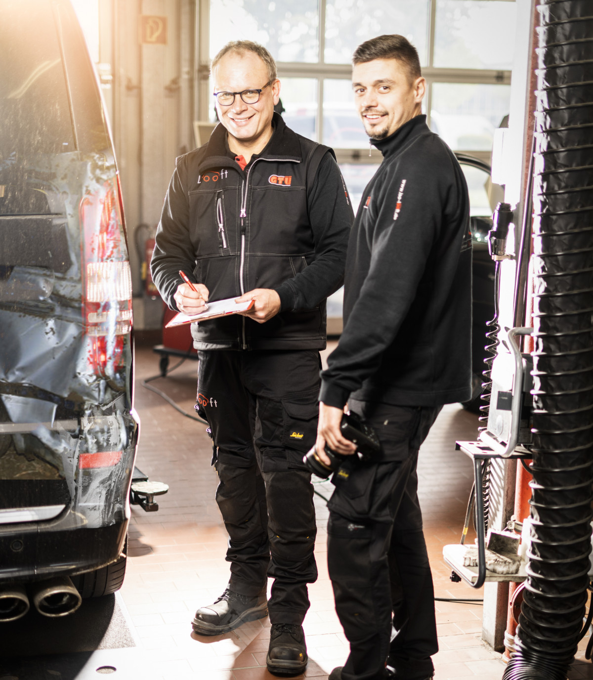 Zwei Werkstatt-Mitarbeiter begutachten ein Fahrzeug