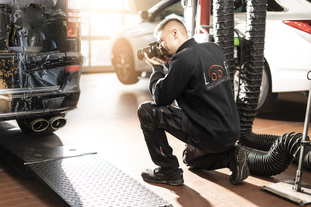 Ein Mitarbeiter fotografiert den Schaden an einem Fahrzeug